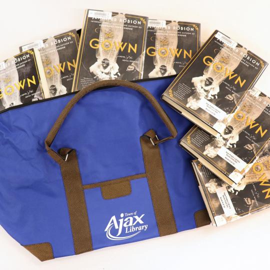 A blue Library duffel bag with seven copies of The Gown by Jennifer Robson.
