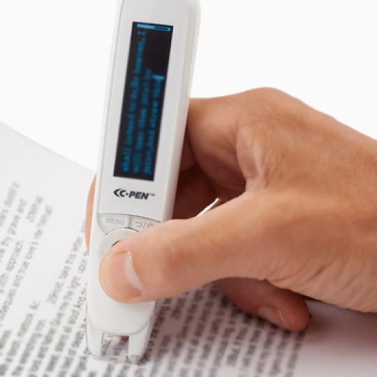A person holding a c-pen and using it to scan text in a book. 
